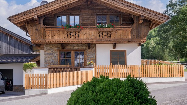 A wooden chalet with a balcony, stone facade, and a wooden fence. - Double room - Ferienhof Stadlpoint (Ried im Zillertal)