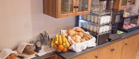 Un buffet de petit-déjeuner comprenant du pain, des viennoiseries et des fruits.