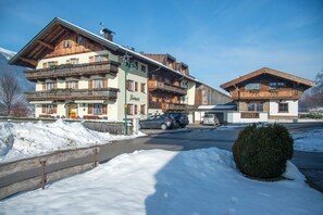 Un hôtel à plusieurs étages, doté de balcons, dont le sol est recouvert de neige, et où sont garées des voitures.