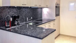A modern kitchen with granite countertops, stainless steel appliances, and light wood cabinets. - Castagnola (Utoring) by Interhome (Castagnola)