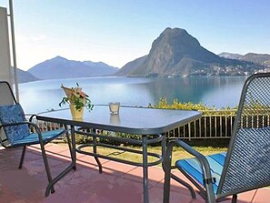 A patio with a table and chairs overlooking a lake and mountains. - Castagnola (Utoring) by Interhome (Castagnola)