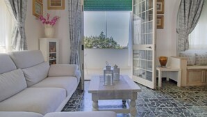 Una sala de estar moderna con un sofá, una mesa de centro y vistas a un espacio exterior a través de un ventanal.