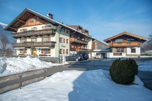 A multi-story hotel with balconies, a snow-covered ground, and parked cars.