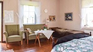 A cozy room with a green patterned sofa, a wooden table with a white tablecloth, and a floral bedspread. - Awesome home in Ryd with house sea view (Ryd)