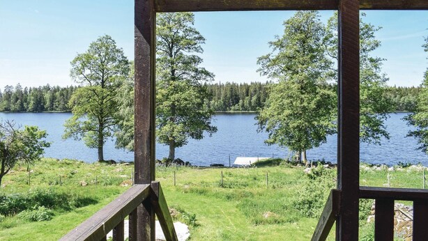 A wooden deck overlooking a lake with trees and a dock. - Awesome home in Ryd with house sea view (Ryd)