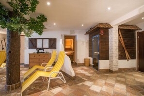 Una habitación con suelo de piedra, muebles de madera y un árbol.