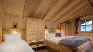 Una cabaña de madera con dos camas, un armario empotrado y un ventanal con cortinas.