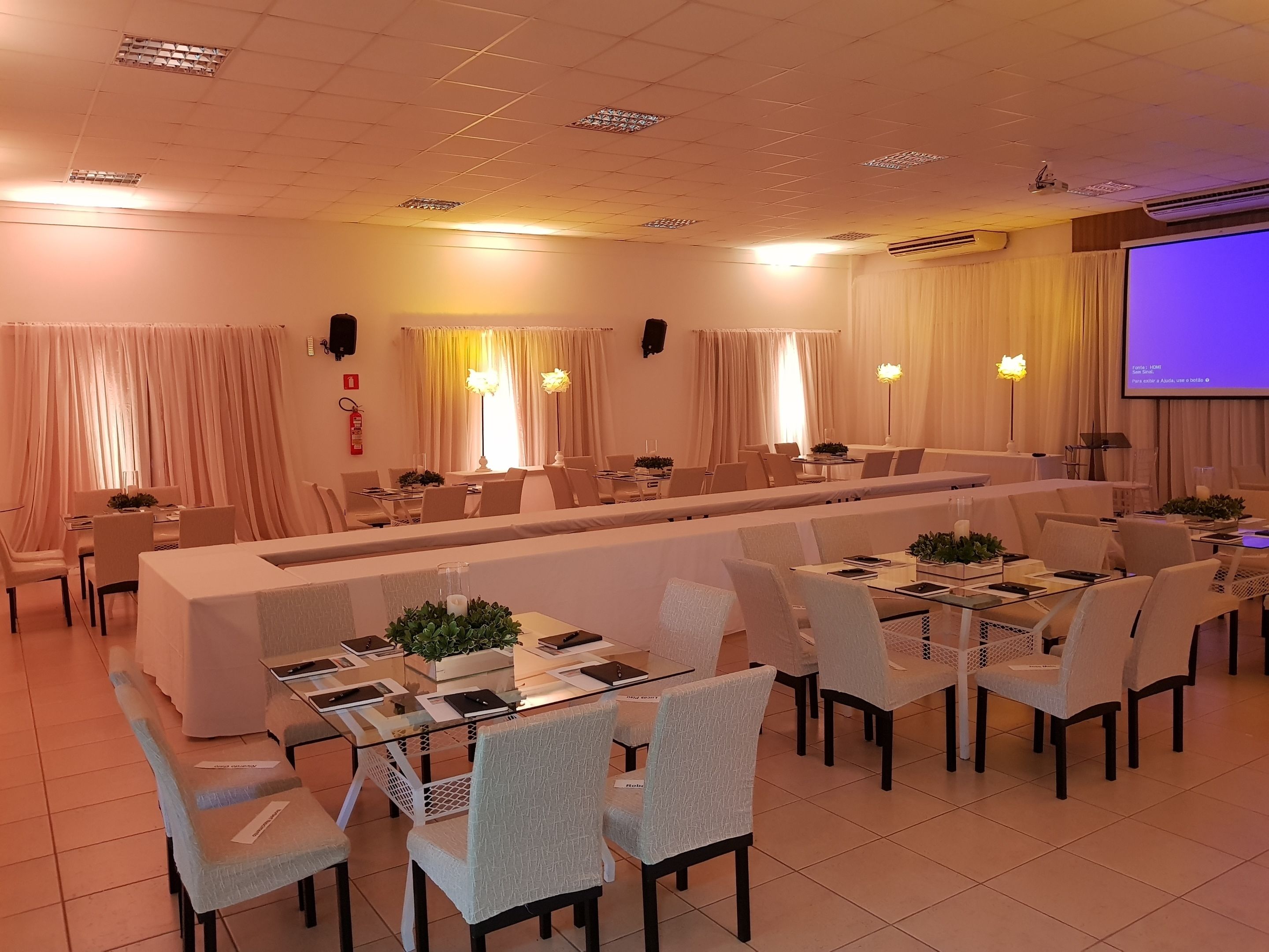 A conference room with a long table, chairs, and a projector screen.