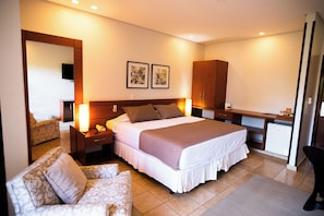 A hotel room with a bed, bedside tables, a desk, a chair, and artwork on the wall. - Palmeiras Comfort Hotel (Paracatu)