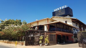 A hotel with a prominent sign, a covered entrance, and a decorative fence. - Hotel das Palmeiras (Paracatu)