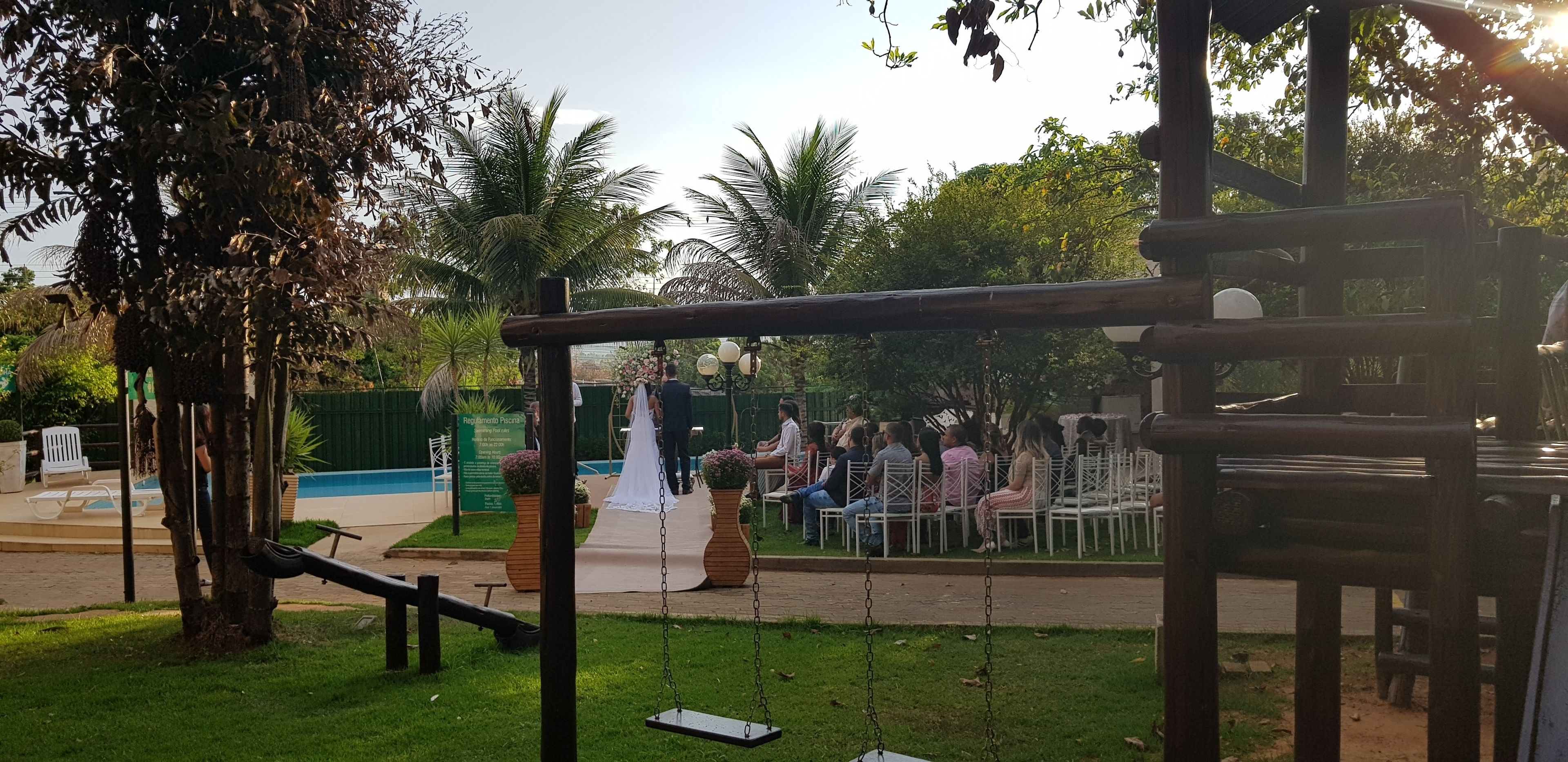 A garden with a swing set, seating area, and a pathway leading to a pool.