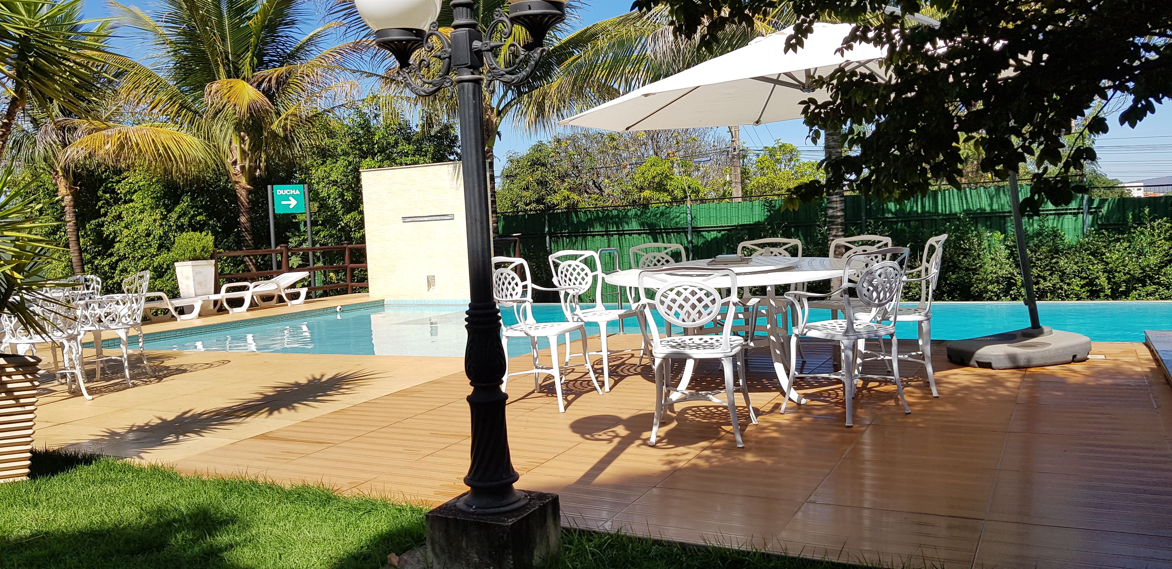 A poolside area with a table and chairs, a lamp post, and a sign pointing to the pool.