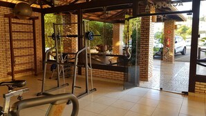 A gym with a brick wall, a weight bench, and a squat rack. - Hotel das Palmeiras (Paracatu)