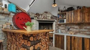 A kitchen with a stone wall, wooden cabinets, a built-in oven, and a wooden log centerpiece. - Villa Levanda *** villa in Makarska, private pool (Makarska)