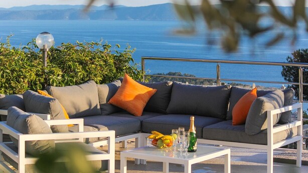 A sofa set with cushions, a glass table with a bottle and glasses, and a view of the sea. - Villa Levanda *** villa in Makarska, private pool (Makarska)