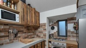 A kitchen with wooden cabinets, a microwave, a stove, and an oven. - Villa Levanda *** villa in Makarska, private pool (Makarska)