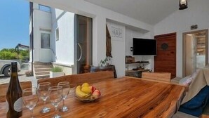 A modern dining area with a wooden table, wine glasses, and a fruit bowl. - Villa Levanda *** villa in Makarska, private pool (Makarska)