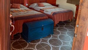 Une chambre avec deux lits, un ventilateur de plafond et une fenêtre avec des rideaux.