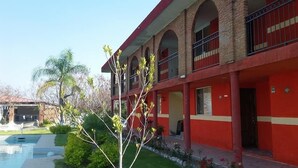 Un immeuble à la façade rouge, doté de nombreux balcons, avec une piscine en premier plan.