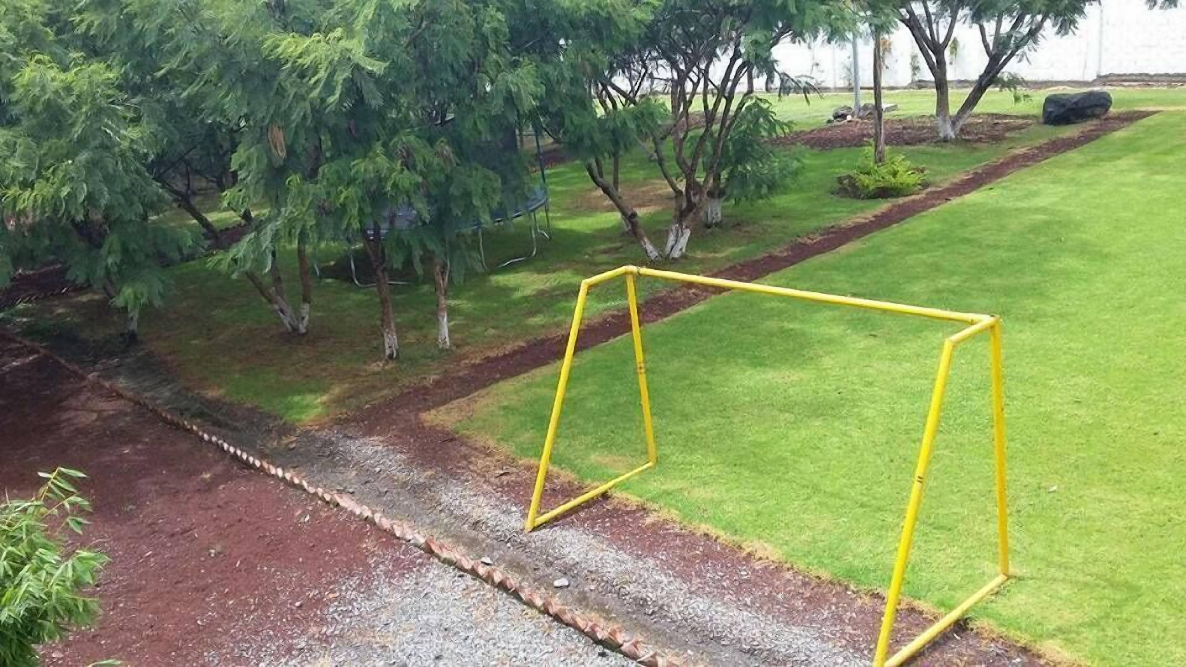 A yellow metal structure in a landscaped area with grass and trees.