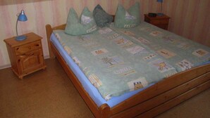 A bedroom with a single bed, a nightstand, a lamp, and a small table with a lamp. - Apartment 1 - Apartments Tovar (Wittmund)