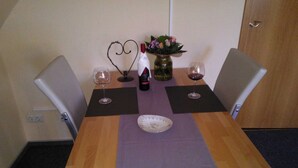 A dining table with two chairs, a vase with flowers, two wine glasses, and a heart-shaped decoration. - Apartment 1 - Apartments Tovar (Wittmund)