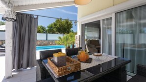 A patio with a table, wicker chairs, a glass-top table, a basket, and a bottle. - Luxurious home in Kornic (Kornic)