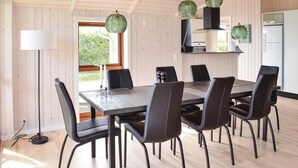 Un comedor con una mesa rectangular, seis sillas y lámparas colgantes.
