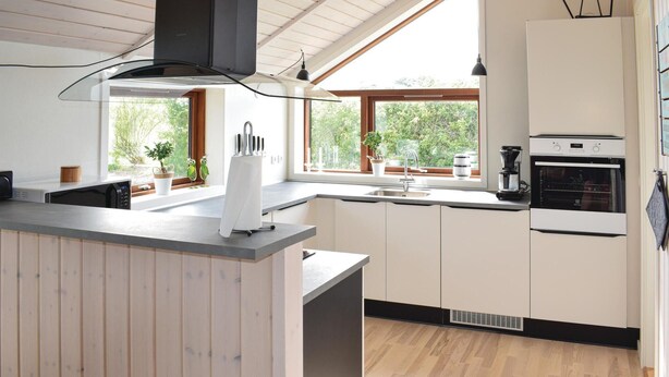 Una cocina moderna con armarios de madera, horno empotrado y ventana que proporciona luz natural.