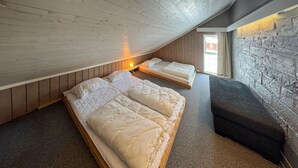 Een slaapkamer in loftstijl met twee bedden en een bank, met houten lambrisering en een stenen muur.