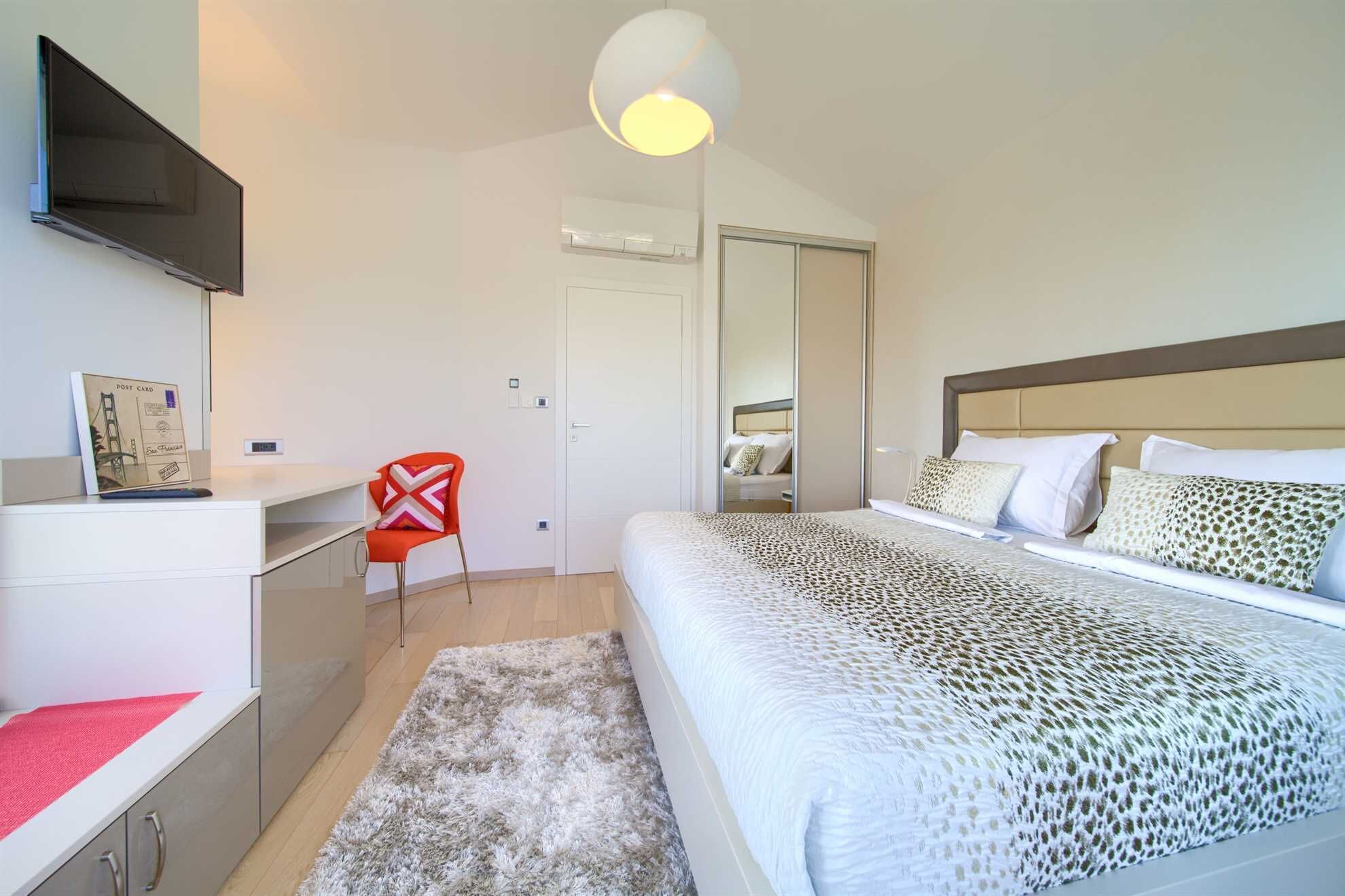 Une chambre à coucher moderne, équipée d’un lit, d’un bureau, d’une chaise et d’un téléviseur.