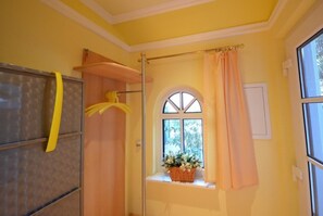 Relax in a serene space with a window offering a view, a shelf holding a vase of fresh flowers, and a convenient towel rack.