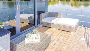 Una terraza con mobiliario de mimbre y una mesa con una bandeja de objetos.