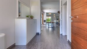 Ein moderner Flur mit einer Holztür, einem weißen Schrank mit Spiegel und einem Essbereich mit Tisch und Stühlen.