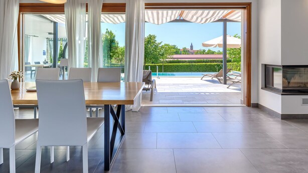 Ein moderner Essbereich mit Blick auf Pool und Garten.