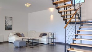 Ein modernes Wohnzimmer mit einem weißen Sofa, einem Couchtisch und einer Treppe mit Holzstufen.