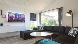 Ein modernes Wohnzimmer mit einer Eckcouch, einem runden Couchtisch und einem Stadtbild an der Wand.