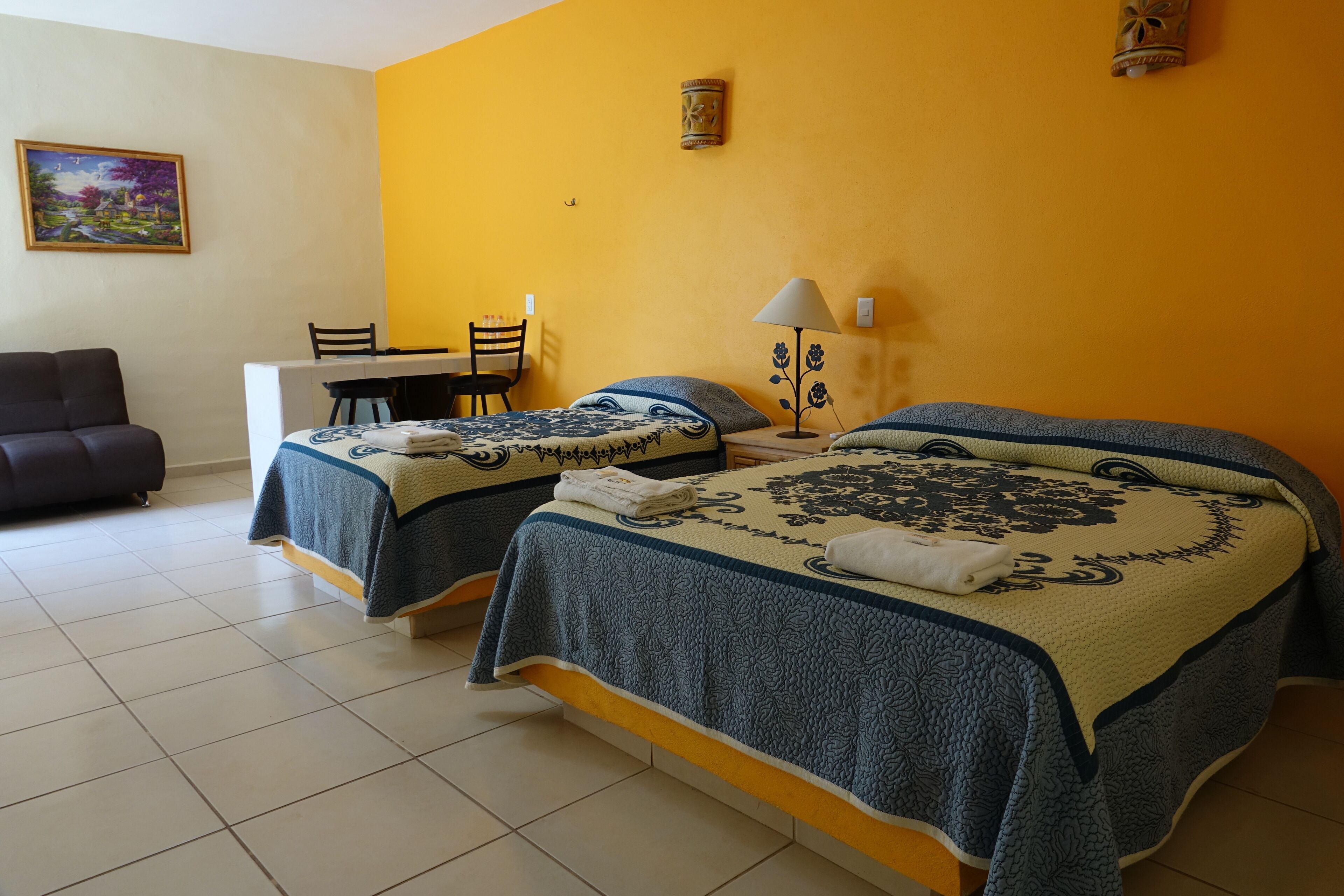 Una habitación con dos camas, un escritorio, una silla y un sofá.
