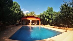 A swimming pool with a covered area, surrounded by trees and a clear sky. - Quinta Comala (Comala)