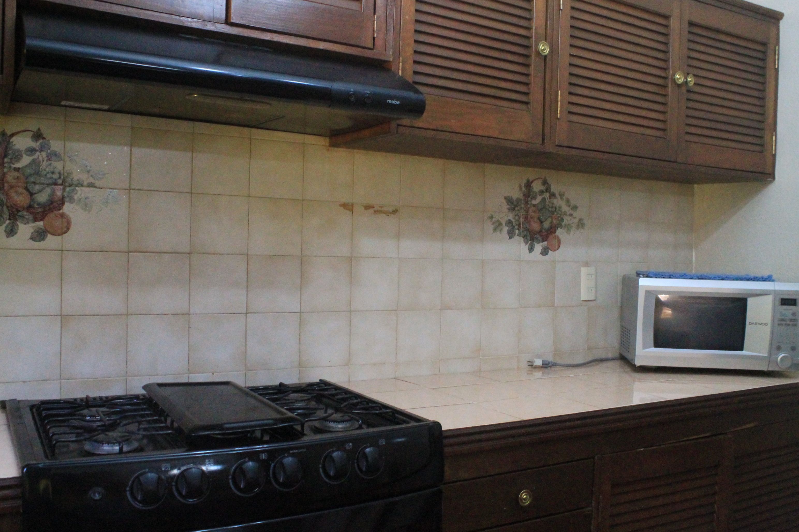 A kitchen with a stove, microwave, and wooden cabinets.