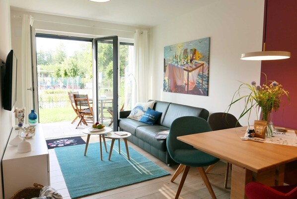 Un salon avec un canapé, une table à manger, un téléviseur et un tableau accroché au mur.