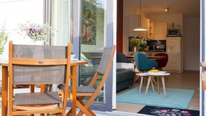 A modern living room with a sofa, a dining table, and a kitchen area with cabinets and appliances.