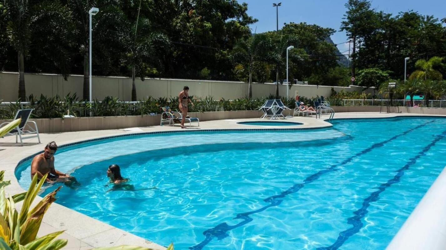 A swimming pool with clear blue water, surrounded by lounge chairs and palm trees.