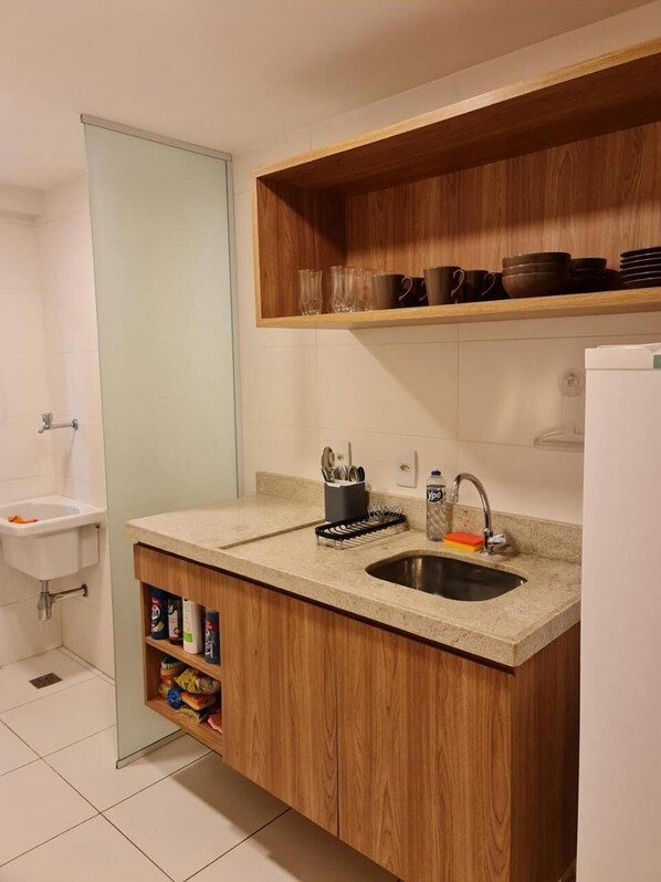 A compact kitchen with a built-in sink, wooden cabinets, and a countertop.