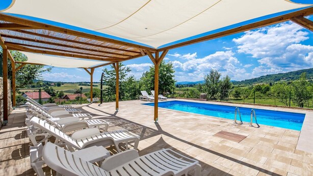 Un espacio al aire libre cubierto con piscina, sillas de descanso y vistas al campo.
