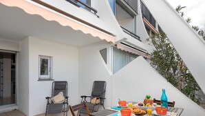 Um pátio com uma mesa posta para o café da manhã, duas cadeiras e um pequeno jardim.