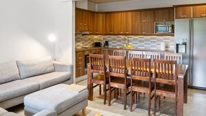 Una cocina moderna con armarios de madera, microondas integrado y un refrigerador de acero inoxidable.