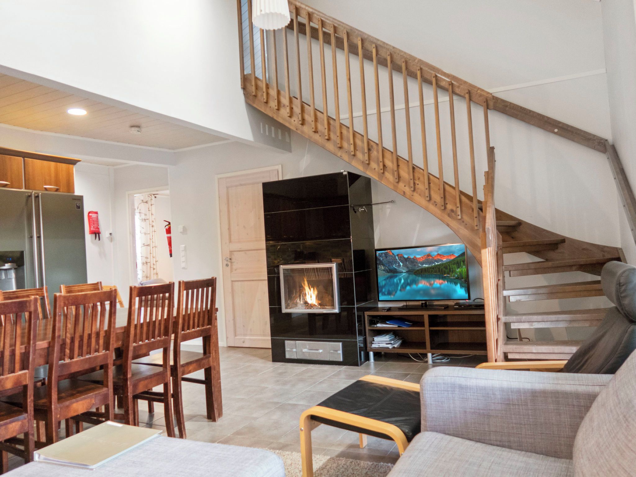 Una sala de estar con chimenea, televisor, muebles de madera y una escalera.