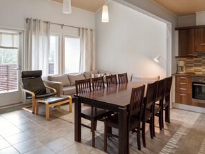 Uma sala de estar moderna com uma mesa de jantar, cadeiras, um sofá e uma área de cozinha.