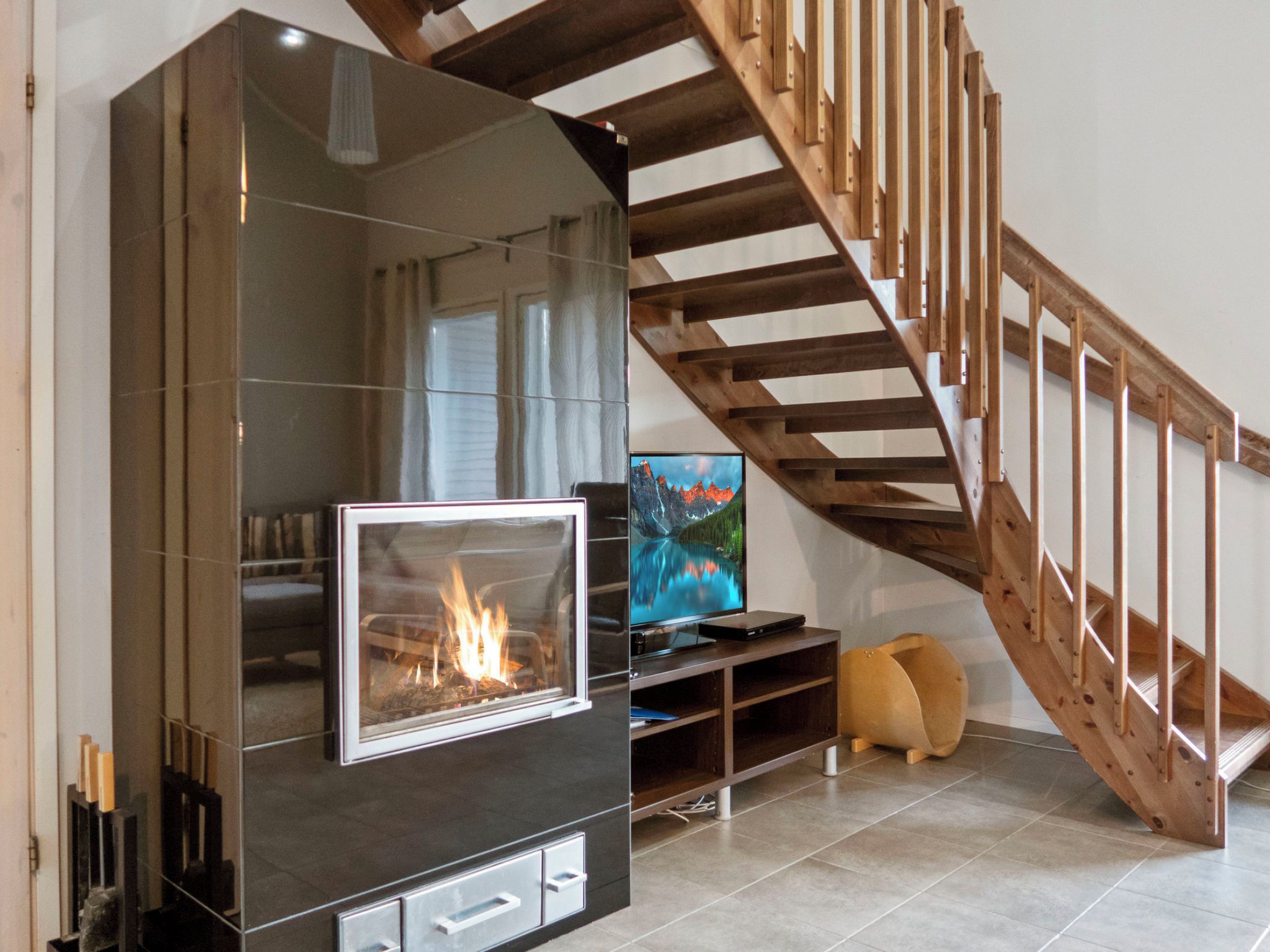 Un salon moderne avec une cheminée, un escalier en bois et un téléviseur à écran plat.